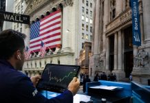 trader che lavora con sullo sfondo Wall Street e Borsa Italiana